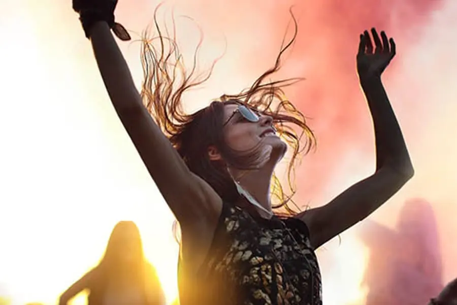 Image of a woman wearing sunglasses dances with her hair flying at a music festival. Symbolizing the effect of using Thone headphones. In partnership with Stars and Stories, the company gained genuine customer feedback